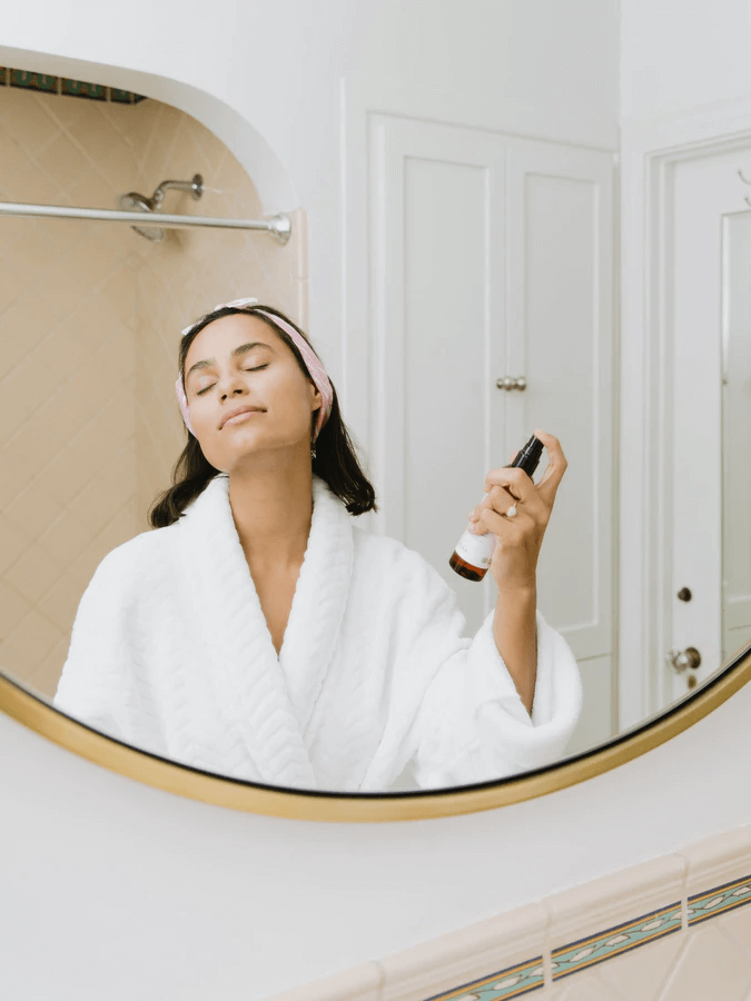 A woman spritzing toner on her face